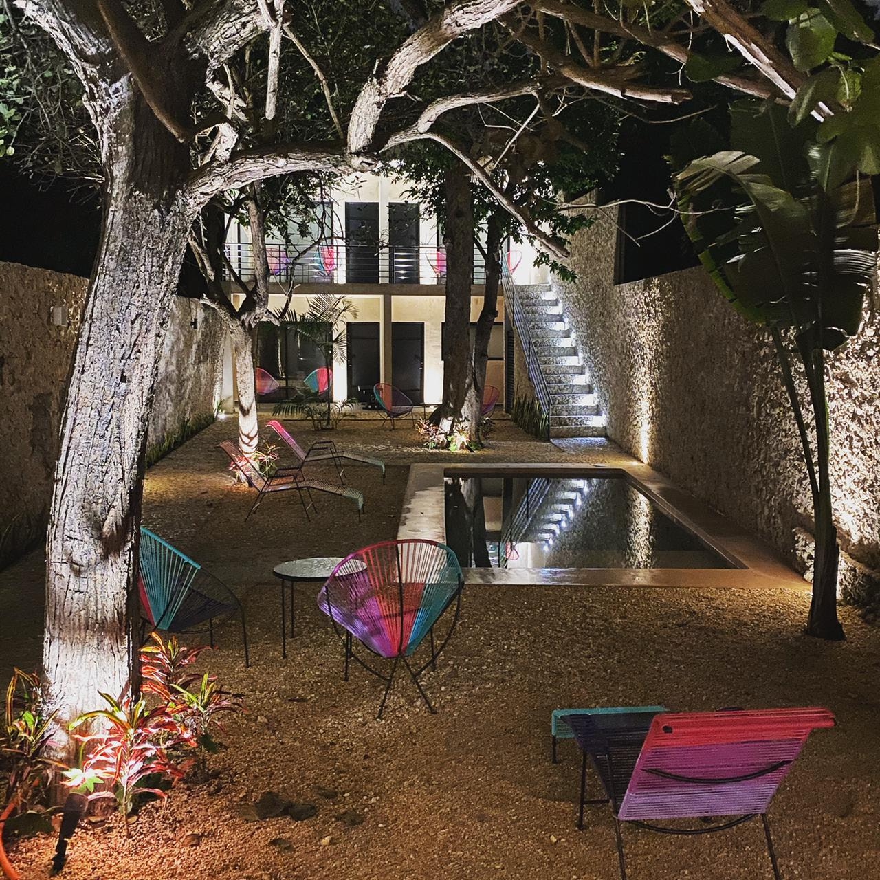 Hotelito Yum Kaax — jardín nocturno con alberca y árboles